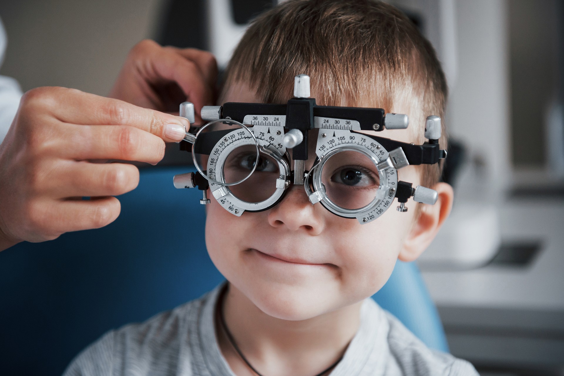 Tuning the intrument. Little boy with phoropter having testing his eyes in the doctor's office